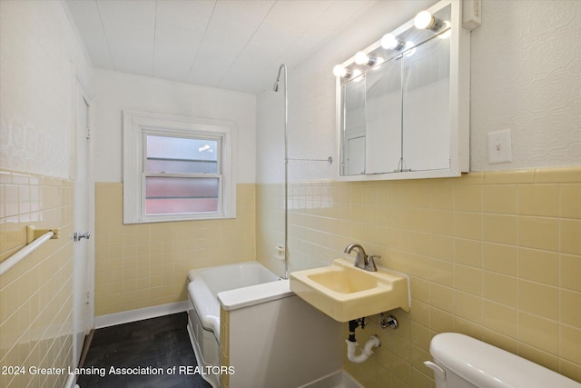 bathroom featuring toilet, tile walls, a bathing tub, and sink