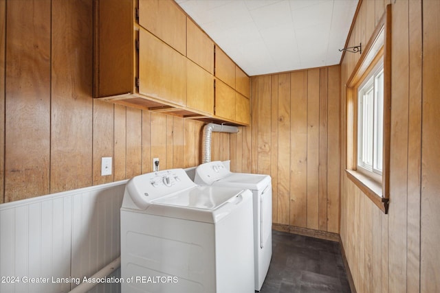 laundry area with cabinets, washer and clothes dryer, and wood walls