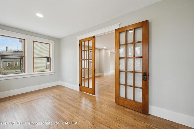 empty room featuring french doors and light hardwood / wood-style flooring