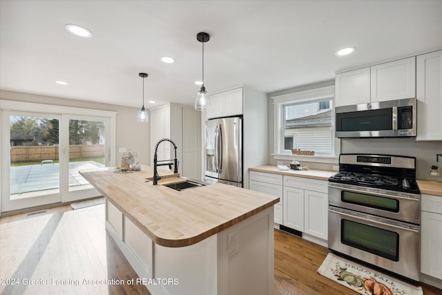 kitchen featuring sink, hanging light fixtures, a center island with sink, white cabinets, and appliances with stainless steel finishes