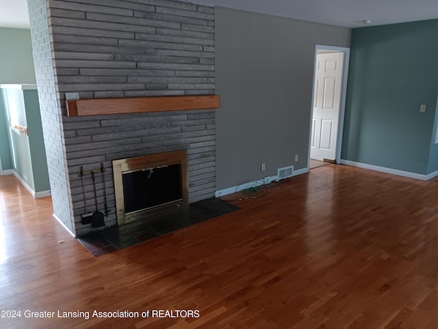 unfurnished living room featuring a fireplace and dark wood-type flooring