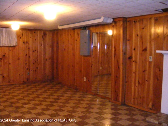 basement with electric panel and wood walls