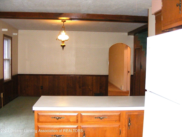 kitchen with carpet flooring, white refrigerator, decorative light fixtures, and wooden walls