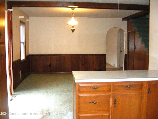 kitchen featuring kitchen peninsula, wood walls, hanging light fixtures, and light carpet