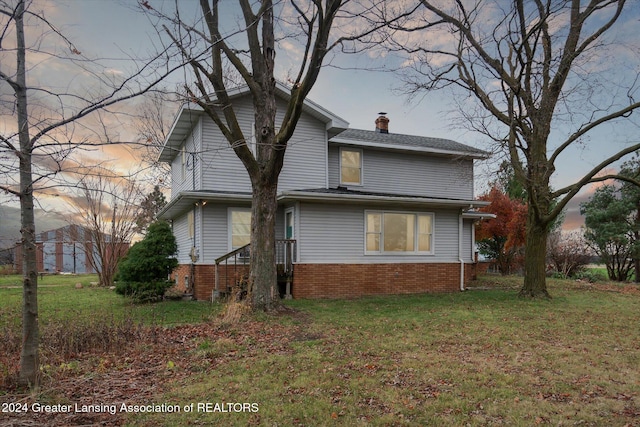 property exterior at dusk featuring a lawn