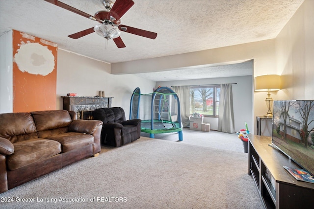 living room with ceiling fan, carpet, and a textured ceiling