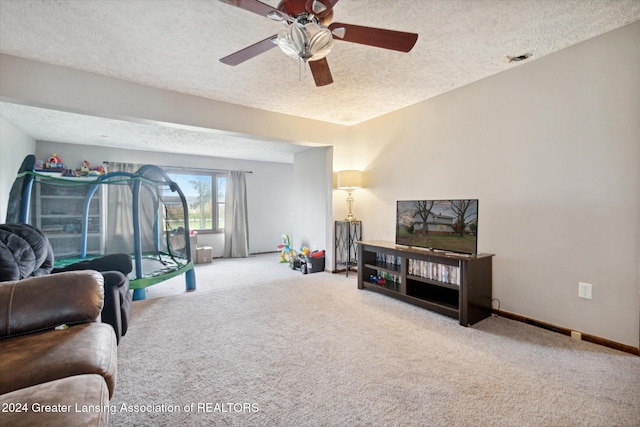 carpeted living room with ceiling fan and a textured ceiling