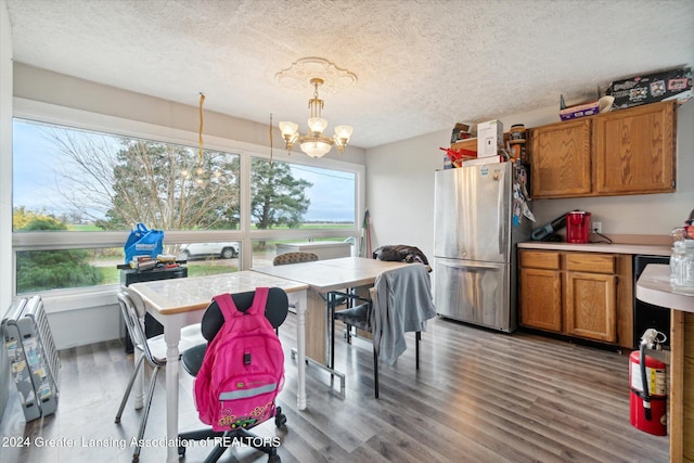 kitchen featuring stainless steel refrigerator, hanging light fixtures, an inviting chandelier, wood-type flooring, and a textured ceiling