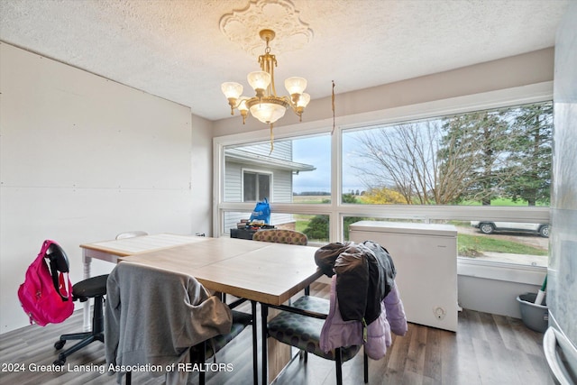 dining area with a chandelier, a textured ceiling, and hardwood / wood-style flooring