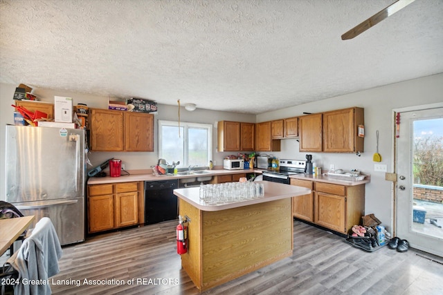 kitchen featuring pendant lighting, a center island, light wood-type flooring, and stainless steel appliances