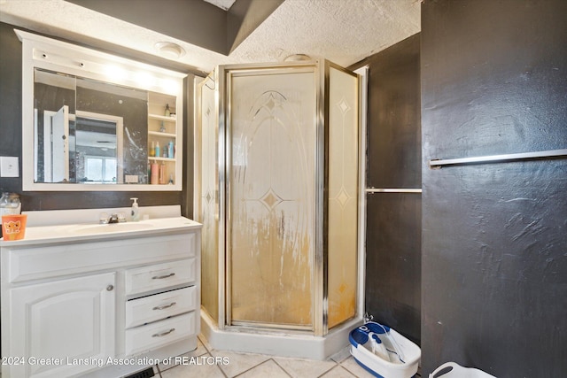 bathroom featuring tile patterned flooring, vanity, a textured ceiling, and walk in shower