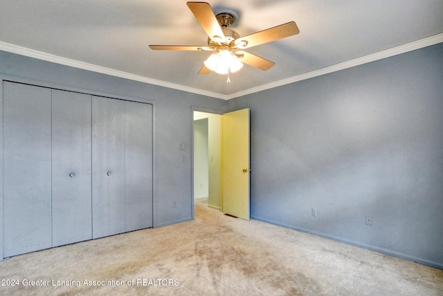 unfurnished bedroom with ceiling fan, a closet, light colored carpet, and crown molding