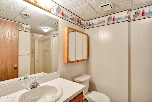 bathroom featuring a paneled ceiling, vanity, walk in shower, and wooden walls