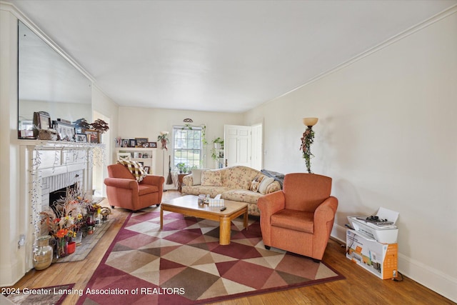 living room with hardwood / wood-style floors, ornamental molding, and a brick fireplace