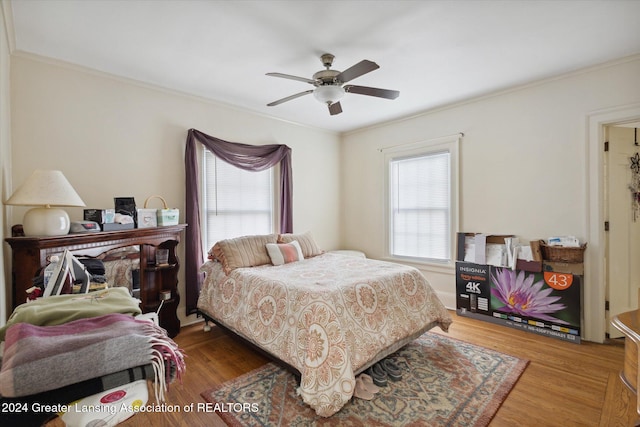 bedroom with wood-type flooring, multiple windows, crown molding, and ceiling fan