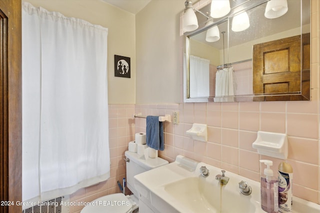 bathroom with vanity, toilet, and tile walls