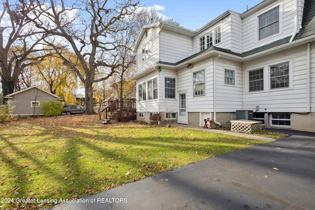 rear view of property with a lawn and central air condition unit