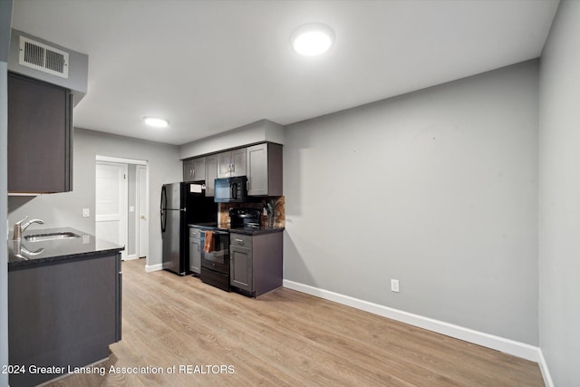 kitchen with black appliances, decorative backsplash, light wood-type flooring, and sink