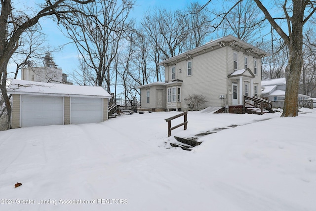 snow covered property with an outbuilding and a garage