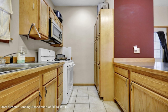 kitchen featuring light tile patterned flooring, sink, and white range with gas cooktop