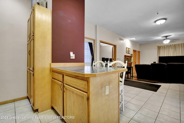 kitchen with ceiling fan, a kitchen bar, kitchen peninsula, and light tile patterned floors