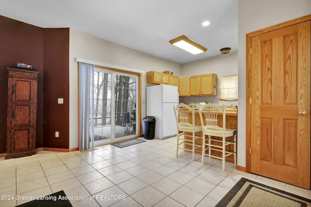 kitchen featuring light brown cabinetry, white refrigerator, and light tile patterned floors