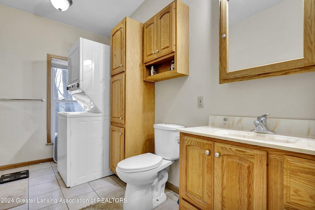 bathroom with tile patterned flooring, vanity, toilet, and stacked washer and clothes dryer