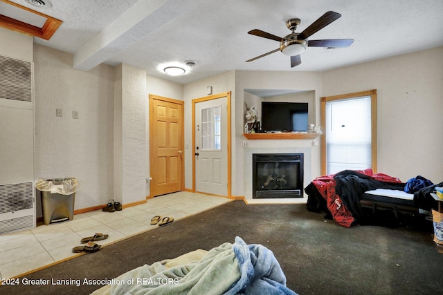 living room featuring ceiling fan, light tile patterned floors, and a textured ceiling