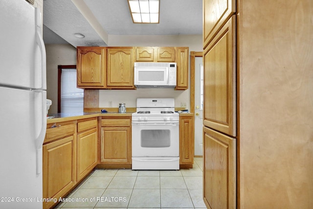 kitchen featuring light tile patterned flooring and white appliances