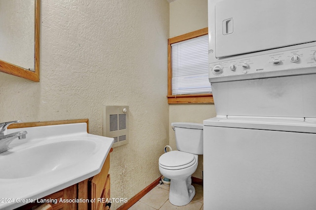 bathroom with tile patterned flooring, vanity, toilet, and stacked washer and clothes dryer