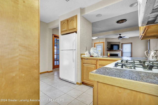 kitchen with ceiling fan, gas stovetop, white refrigerator, light brown cabinetry, and light tile patterned floors