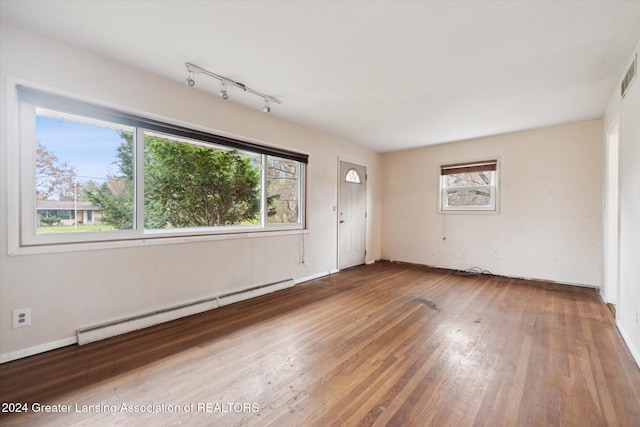 spare room featuring hardwood / wood-style flooring, plenty of natural light, and a baseboard heating unit