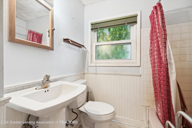 full bathroom with sink, toilet, a textured ceiling, and shower / tub combo with curtain