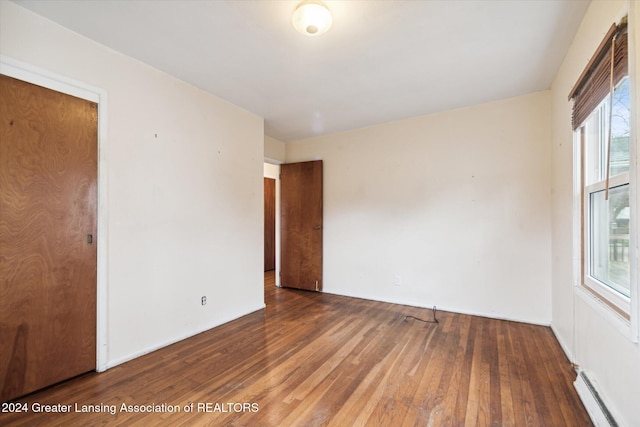 empty room featuring dark hardwood / wood-style flooring and a baseboard radiator