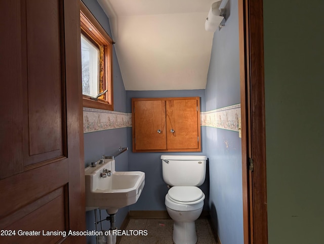 bathroom with tile patterned floors, toilet, lofted ceiling, and sink