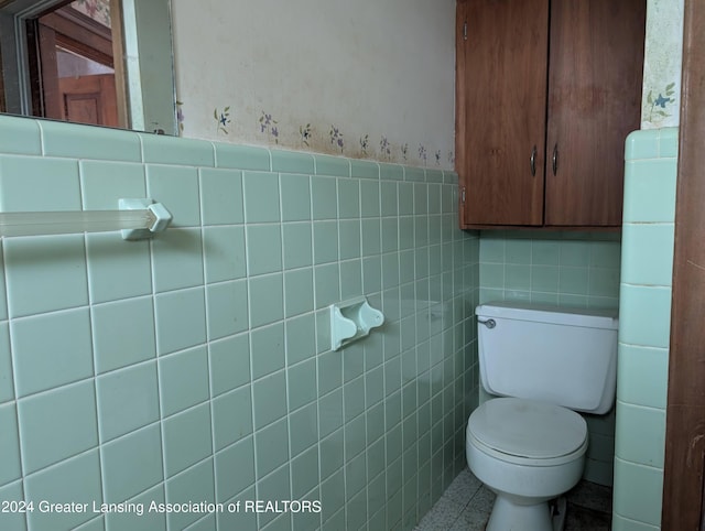 bathroom with tile patterned floors, toilet, and tile walls