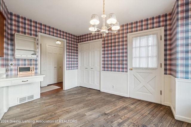 unfurnished dining area with a notable chandelier and hardwood / wood-style flooring