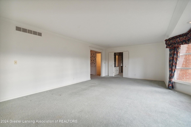 carpeted spare room featuring crown molding