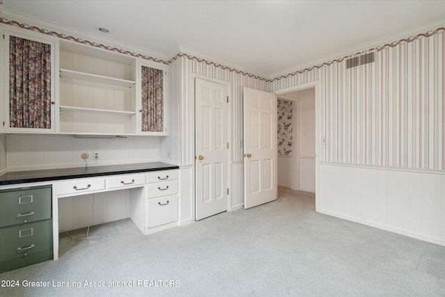 unfurnished office featuring light colored carpet, built in desk, and crown molding