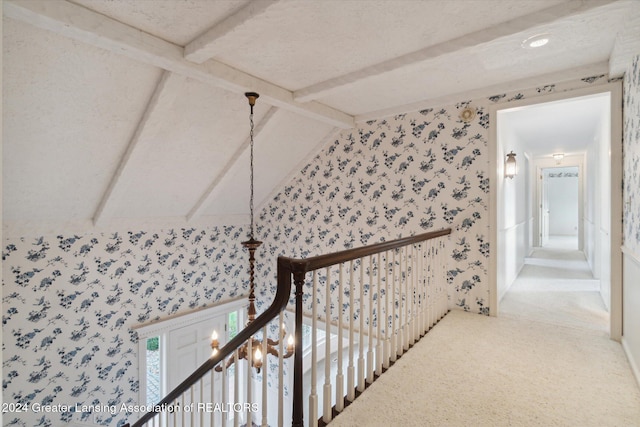 hall with carpet, vaulted ceiling with beams, and a textured ceiling