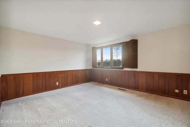 spare room with light carpet and wooden walls