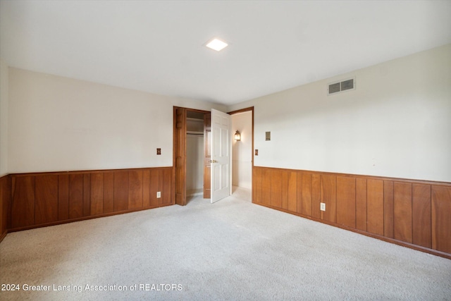 spare room with wood walls and light colored carpet