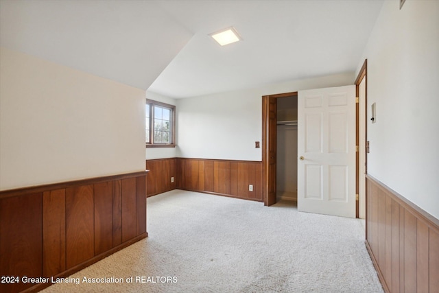 carpeted spare room featuring wood walls