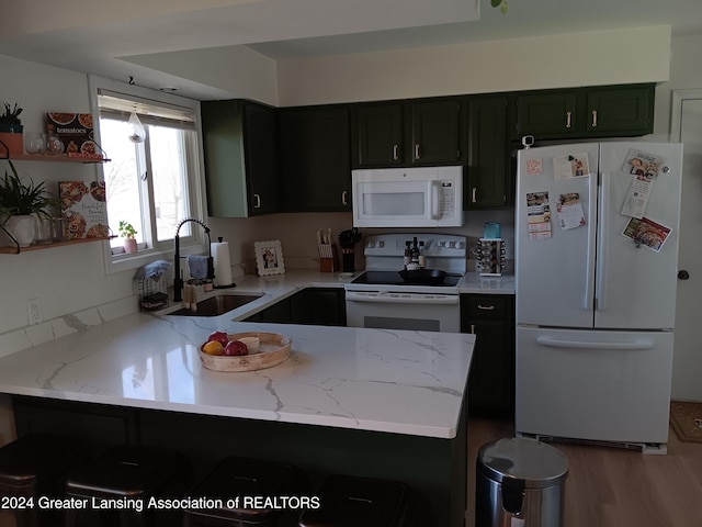 kitchen featuring a breakfast bar area, kitchen peninsula, sink, and white appliances