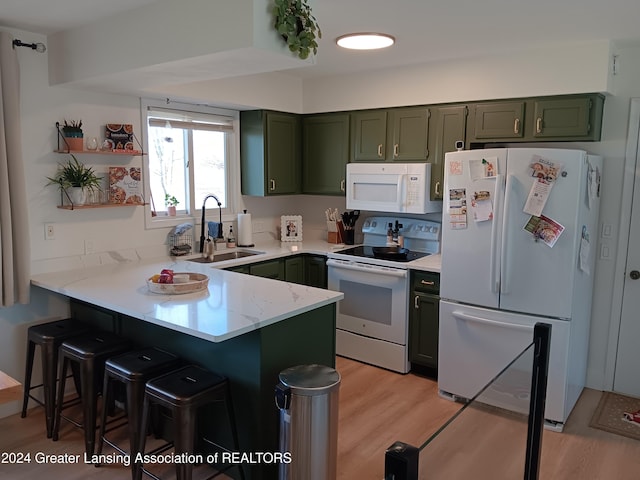 kitchen featuring kitchen peninsula, white appliances, green cabinets, sink, and a breakfast bar area