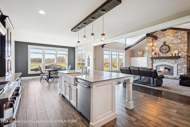 kitchen featuring dark wood-type flooring, white cabinets, a stone fireplace, hanging light fixtures, and range with gas stovetop