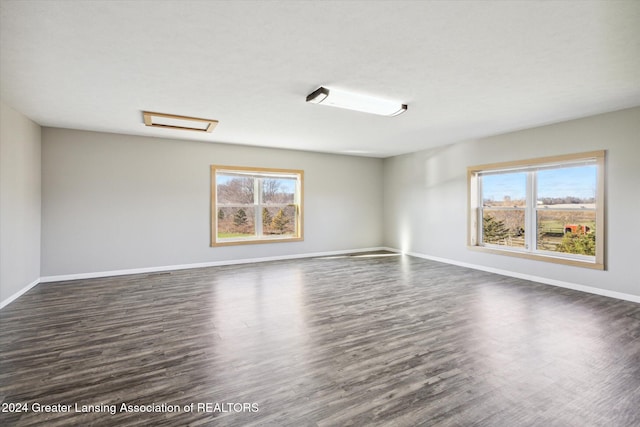 empty room with dark hardwood / wood-style flooring and a healthy amount of sunlight