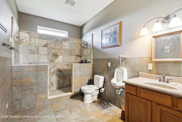 bathroom featuring a tile shower, vanity, tile walls, and toilet