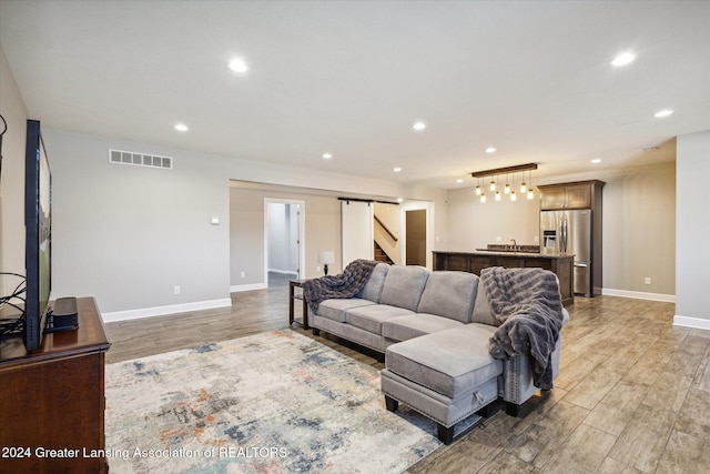 living room with a barn door and hardwood / wood-style flooring