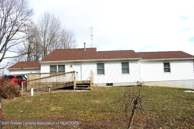 back of house with a wooden deck, roof with shingles, and a yard